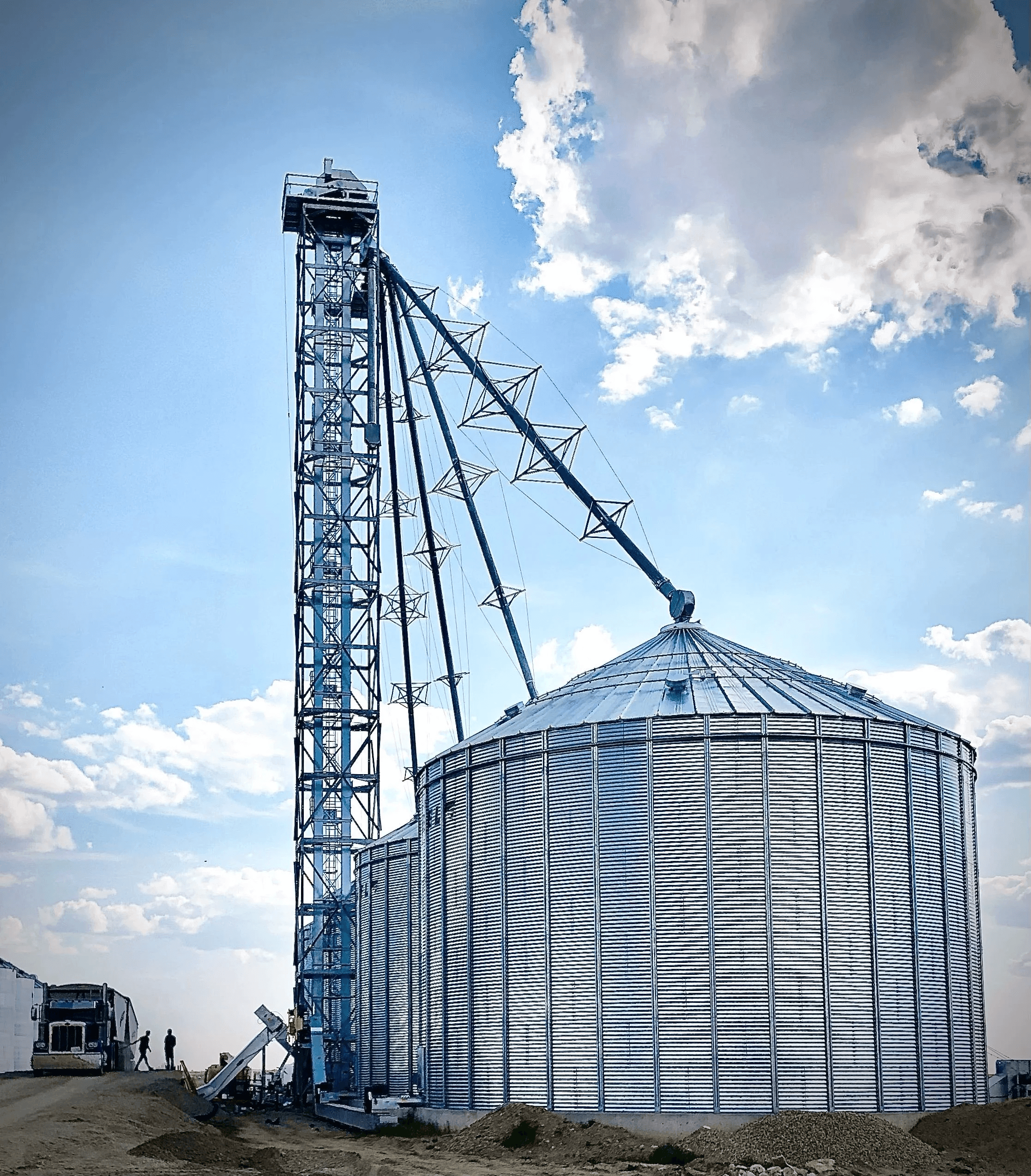 Close view of the galvanized tower and spouting beside a large flat-bottom bin