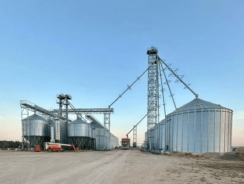 Grain yard with a tall support tower, catwalks and bins at dusk